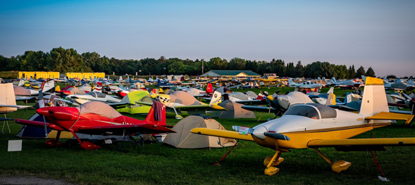 a field of airplanes next to tents on grass